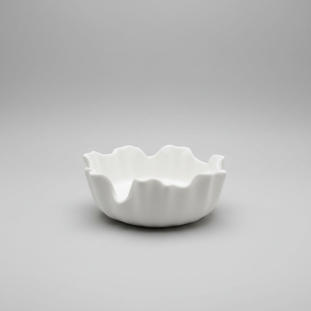 A white ceramic vessel with a wavy, scalloped rim.